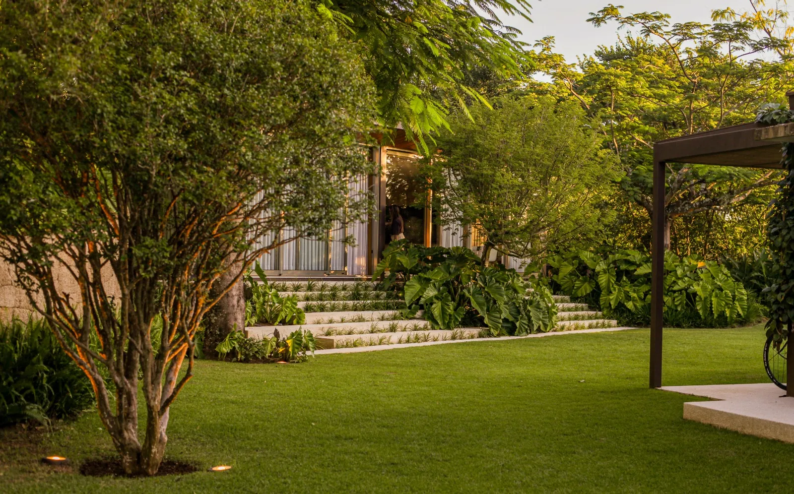 Residência tropical moderna com espelho d'água central e jardim tropical exuberante